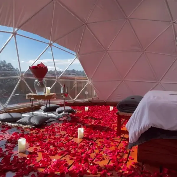 Interior romántico del domo en Conecta Glamping cubierto de pétalos rojos, preparado para una experiencia íntima en pareja