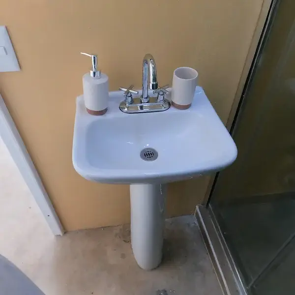 Detalle del lavabo pedestal en el módulo de baño del glamping Las Águilas