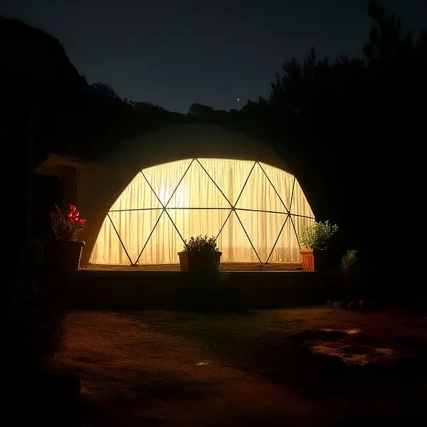 Domo geodésico de Glamping Los Cedros iluminado por dentro durante la noche, mostrando la instalación de iluminación y conexiones de servicios básicos