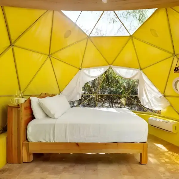 Interior del domo con cama matrimonial y acabado geométrico en color amarillo brillante